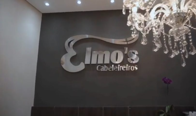 Letreiro Elmo's Cabeleireiros em prata na parede da recepção
