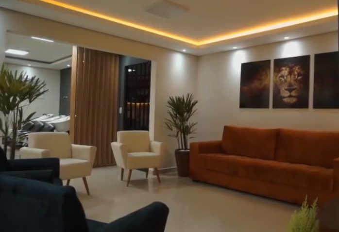 Sala de espera do salão com sofá e quadros decorativos